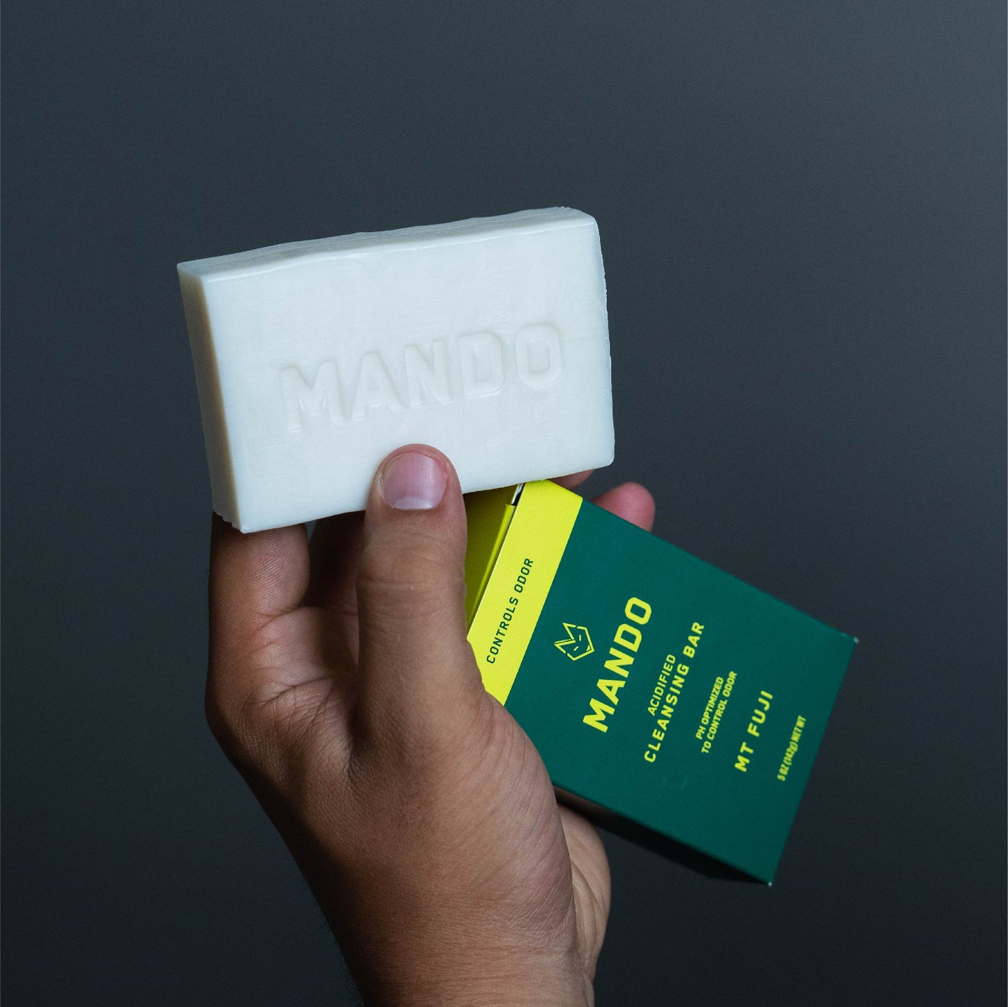 Hands holding bar of Mando 4-in-1 acidified cleansing bar in Mt Fuji scent 