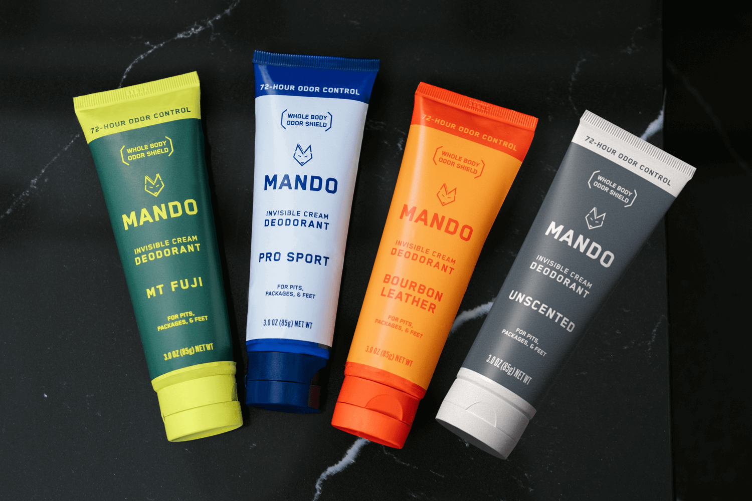 line up of 4 Mando cream deodorants in unscented, bourbon leather, pro sport and mt fuji placed on a marble counter top