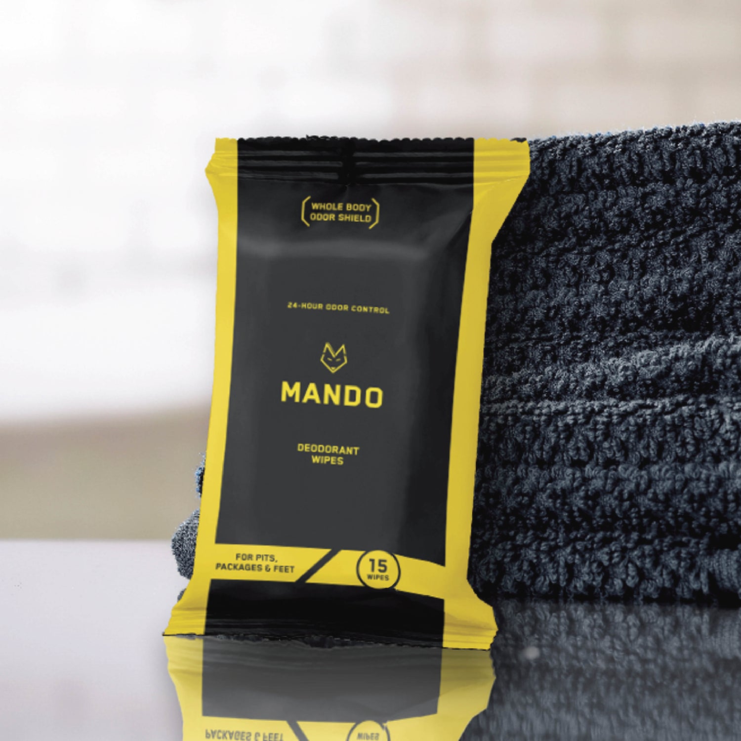 yellow & black pack of Mando 15 count wipes leaning against stack of blue towels 