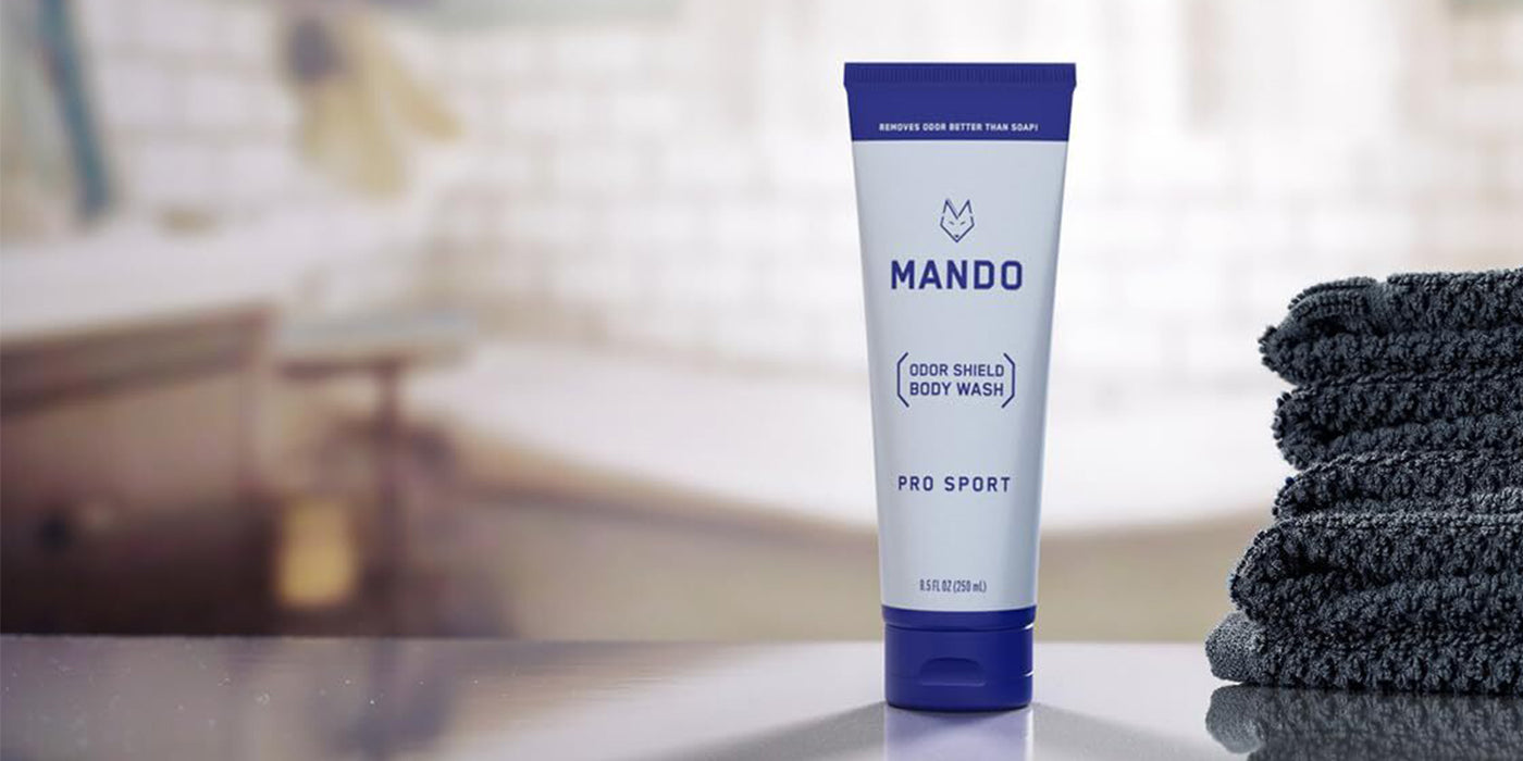 tube of Mando pro sport body wash placed on counter top with blue towels placed beside 