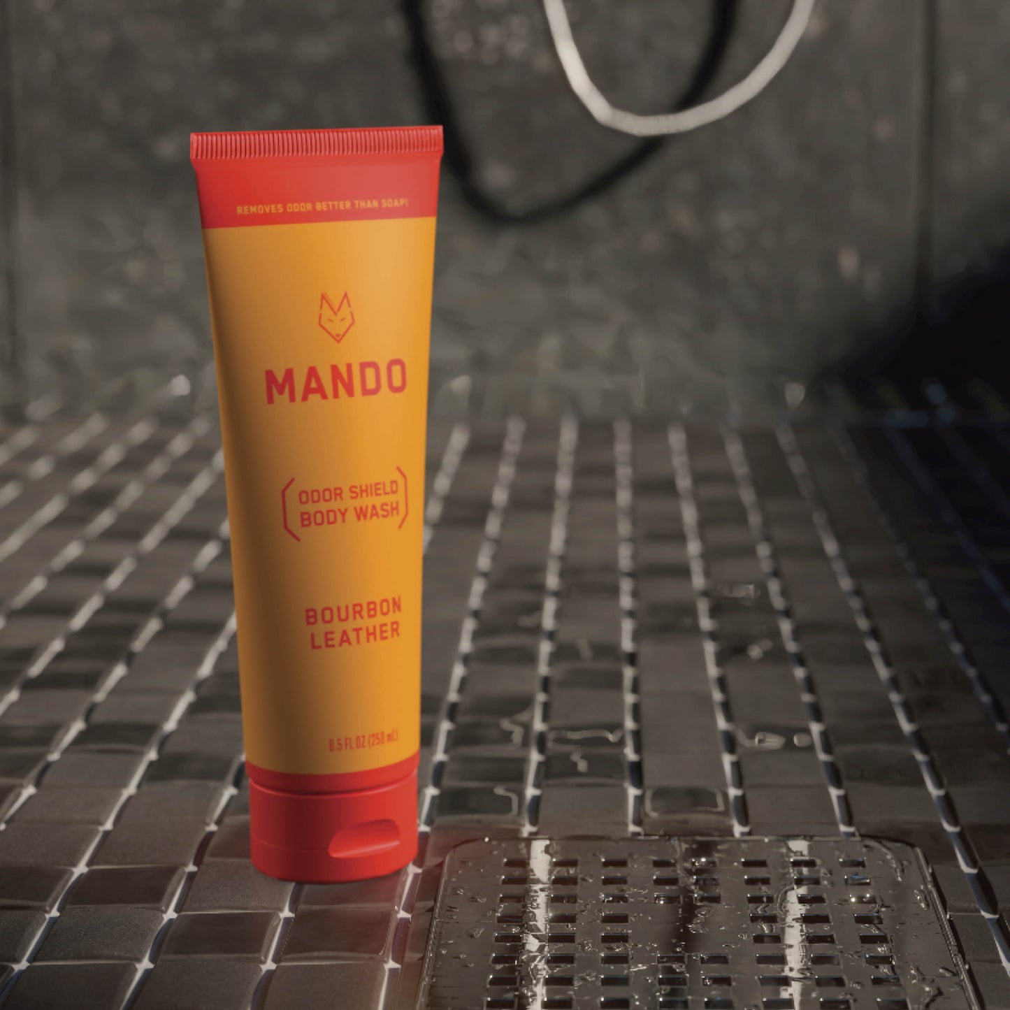 yellow orange tube of Mando body wash in bourbon leather scent standing on shower floor 