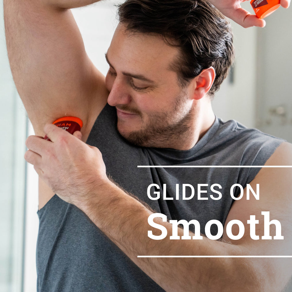 man smiling while applying bourbon leather solid stick deodorant to armpit with text: glides on smooth